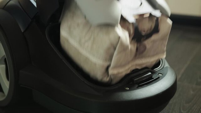 Person performs important household task of replacing vacuum cleaner dust bag, ensuring efficient cleaning power and hygienic home environment for family wellbeing