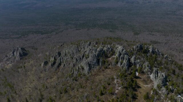 Drone footage of a rugged rocky ridge with sparse pines above vast taiga woodland in Taganay National Park near Zlatoust, Chelyabinsk Oblast, Russia