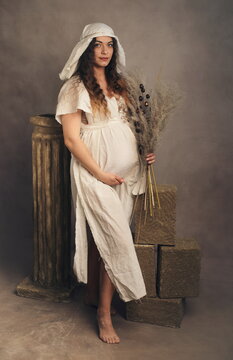 Artistic Full-Length Portrait of Pregnant Woman in Medieval White Gown