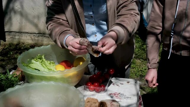 eat a piece of smoked mackerel in the fresh air unwrap separate from the skin on a background of vegetables table in the yard in the garden snack. High quality 4k footage