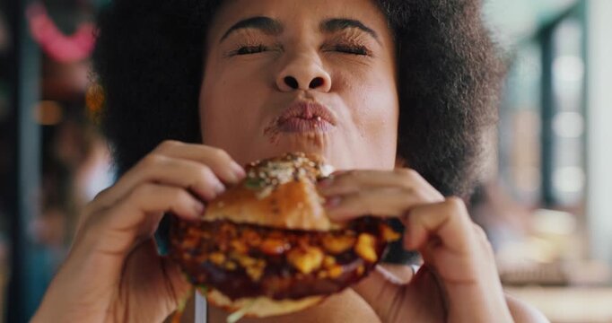 Happy, woman and burger in diner with delicious flavor, tasty cuisine and eating fast food for lunch. Hungry, person or customer in restaurant with beef sandwich, take away or meal for unhealthy diet