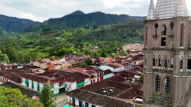 A drone shot starting on the Basilica Menor de la Inmaculada Concepci&oacute;n, panning left to reveal the red-tiled rooftops of Jard&iacute;n and the lush green Andes mountains in the background.