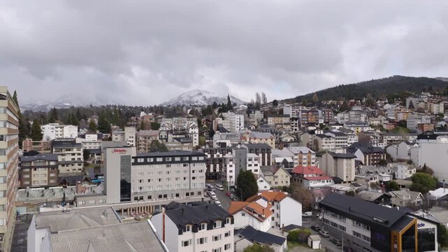 Clouds hover over the cityscape of San Carlos de Bariloche, revealing a mix of modern and traditional architecture. Ideal for urban development or travel documentaries.