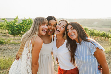 Naklejka premium Group of female friends having fun at summer event in countryside with vineyards in background - Summer vacation, party and travel concept - Focus on girls faces