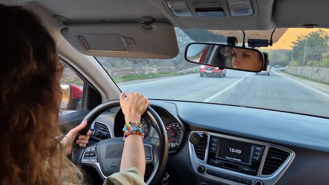 Driving woman road trip scenic journey in a modern car, enjoying the beautiful mountain landscape during sunset.