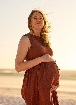 Pregnant Woman Standing on Beach at Sunset Maternity Portrait, Expectant Mother Embracing Belly