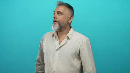 Fototapeta premium Man pointing right with finger in studio against turquoise backdrop, beige linen shirt visible and hand extended; curiosity.
