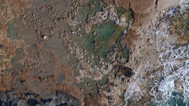 Aerial Top Down View of Rugged Rocky Shore and Crystal Clear Mediterranean Water in Cyprus