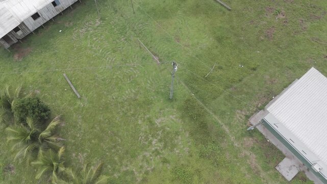 High angle drone shot pulls back over humble dwellings in the Amazon rainforest. Useful for documentaries on poverty, remote living, and South American culture