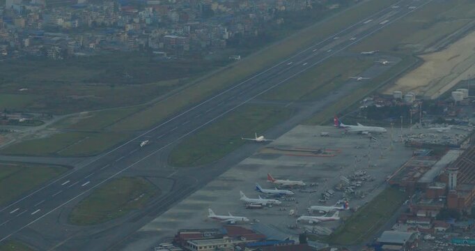 Aerial view of Tribhuvan International Airport in runway, Kathmandu, Nepal , parked airplanes and an unmanaged city covered in thick haze, with poor air quality reducing visibility across the valley.