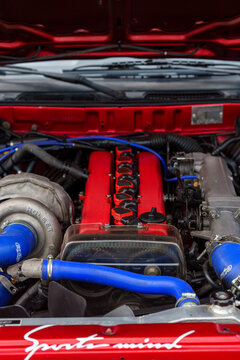 High-performance modified engine bay featuring a large Holset turbocharger, red valve covers, and blue silicone cooling hoses, custom automotive tuning and mechanical engineering concept