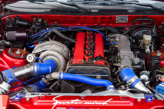 High-performance modified engine bay featuring a large Holset turbocharger, red valve covers, and blue silicone cooling hoses, custom automotive tuning and mechanical engineering concept