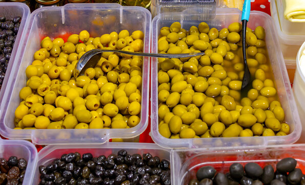 Fermented organic green olives inside plastic containers sold on market
