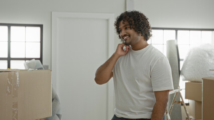 Fototapeta premium Man with cardboard box and bubblewrap removes face mask while unpacking boxes and smiles in a building; relief fresh start.