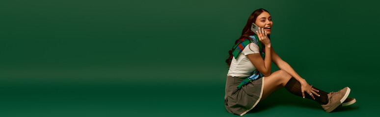 Fototapeta premium Young woman showcases trendy fashion pose in vibrant green studio setting