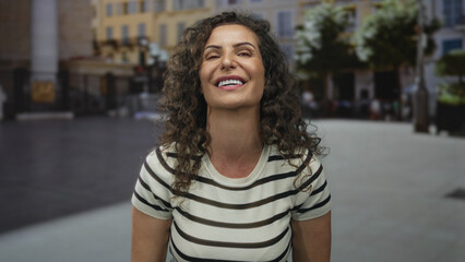 Fototapeta premium Woman with crossed arms on street wearing striped short sleeve top and looking sideways at camera; denial.