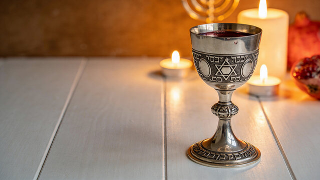 Traditional Jewish kiddush cup with Star of David and candles for Shabbat or Hanukkah celebration
