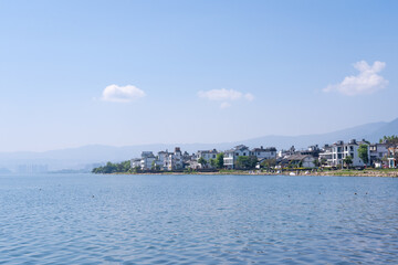 Fototapeta premium lake shoreline with traditional chinese architecture, mountains