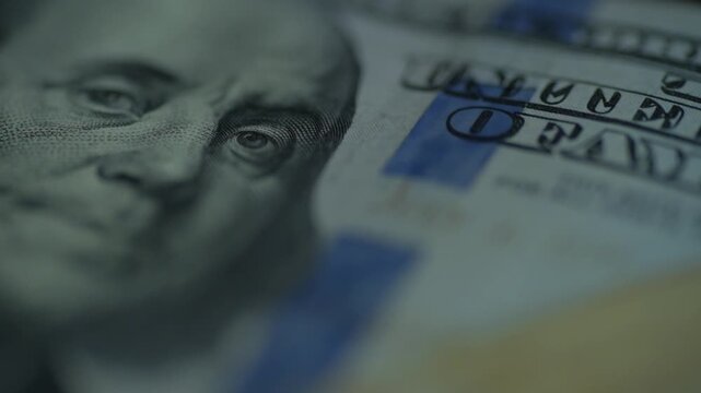 Hundred dollar bill closeup red tint flicker, urgent lighting shifts highlight portrait and ribbon, uneasy color change suggests crisis, dramatic investigative tone
