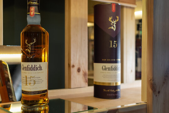 Bottle of Glenfiddich 15 Year Old Our Solera Fifteen single malt whisky on a mirror surface next to its purple tube packaging on a wooden shelf. Ukraine, Zhytomyr, May 04, 2026