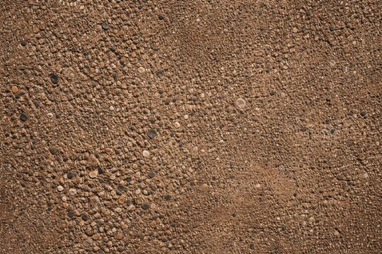 Surface texture of brown concrete with exposed aggregate on rough wall backdrop