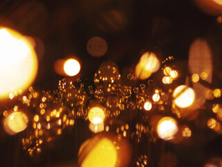 Fototapeta premium Warm glowing fairy lights and glass ornaments with golden bokeh reflections creating festive abstract holiday background