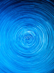 Fototapeta premium Abstract blue spiral light trails and circular long exposure motion effect with futuristic cosmic energy background
