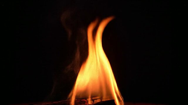 A close-up view of a burning flame in a dark environment shows fire and heat.