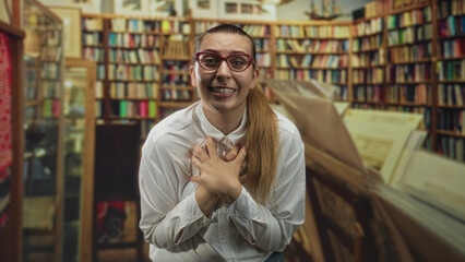 Woman with hands on cheeks reacting beside bookshelves in a bookshop building  excitement discovery. © Krakenimages.com