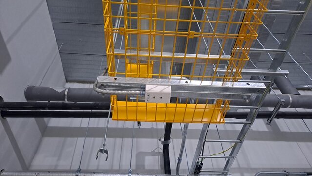 bottom view of yellow basket cable tray and electrical outlet on a data center ceiling