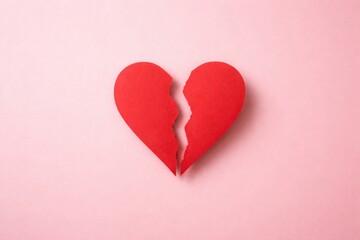Fototapeta premium Top view of separated red heart cut from paper on gentle pink backdrop with ample copy space
