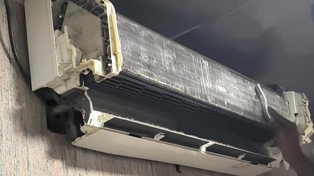 Technician cleaning split air conditioner filter with professional tools during indoor maintenance service. HVAC servicing footage showing dust removal and regular AC maintenance process 