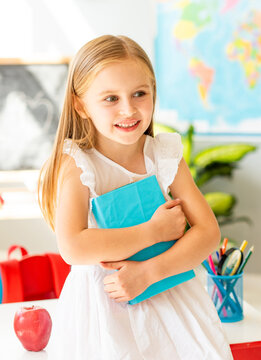 Happy Girl Stands By The Door In A Bright School Classroom