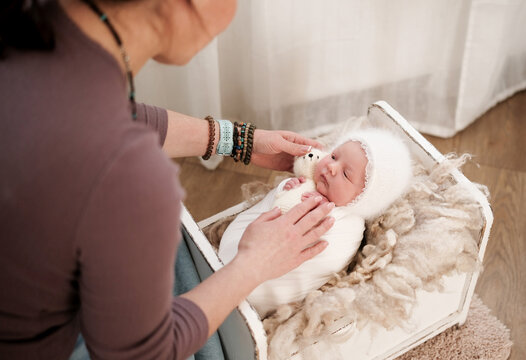 Photographer Placing A Newborn Baby In A Small Crib During A Photoshoot
