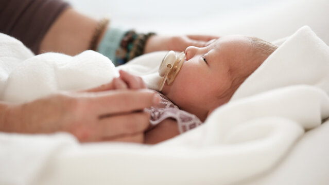 Mom Tenderly Adjusts Soft Covering Around Newborn Baby.