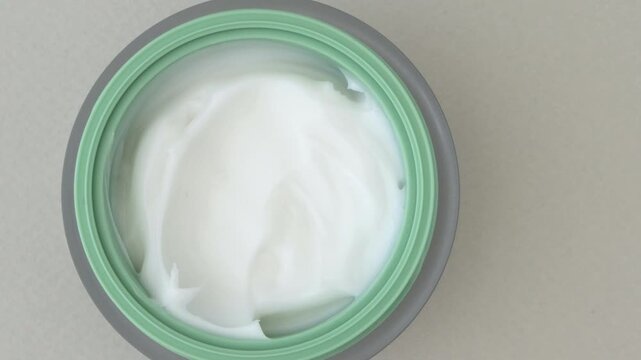 Hand placing facial cream moisturizer jar, close-up top view skincare concept