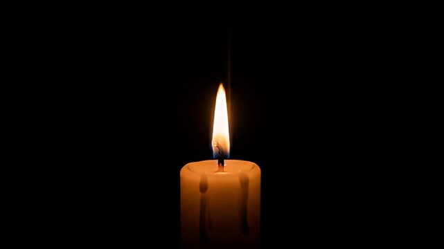 Lit candle with wax drips against a black background, creating a warm, hopeful glow
