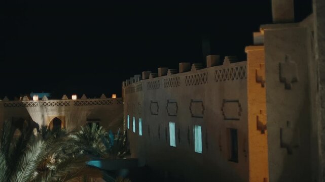 Traditional clay fortress wall with lit windows and decorative battlements at night