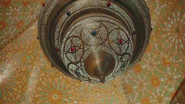 Detailed underside of traditional metal lantern with pierced pattern over zellige tile ceiling