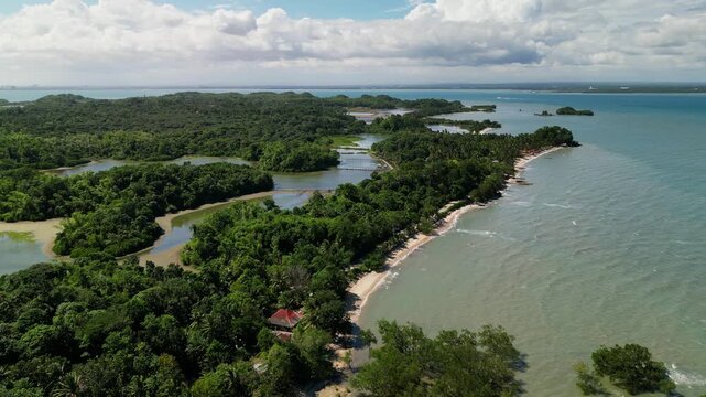 Panoramic aerial flyover of a tropical coastline with mangrove forest, sandy shoreline, and calm ocean waters in Buenavista, Guimaras, Philippines.
