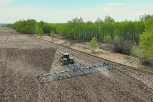 tractor with plow harrows and plows the soil in the field