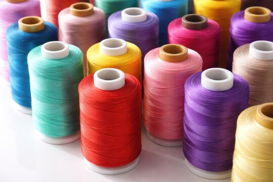Close perspective of multicolored thread spools displayed on stark white surface