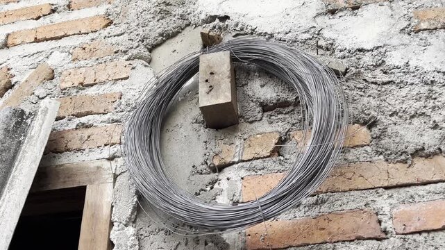 Roll of Steel Binding Wire on Unfinished Brick Wall