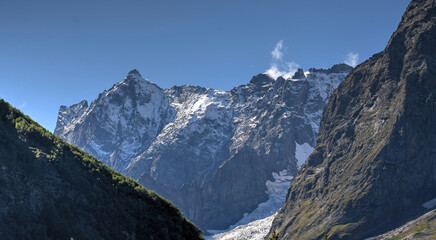 Fototapeta premium The image depicts a mountain landscape. The photo shows majestic rocky peaks, some of which are covered in snow or glaciers
