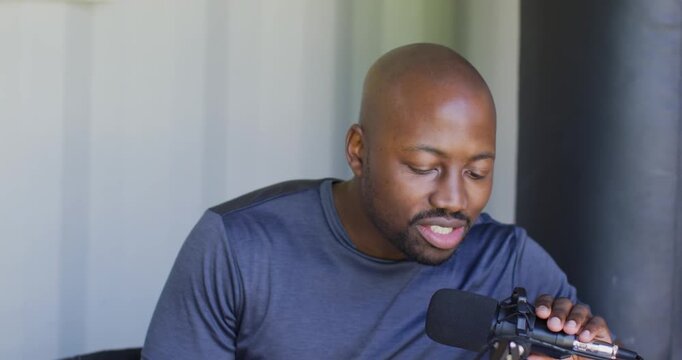 Man preparing to record in studio, leaning toward mic, adjusting shock mount and checking notes