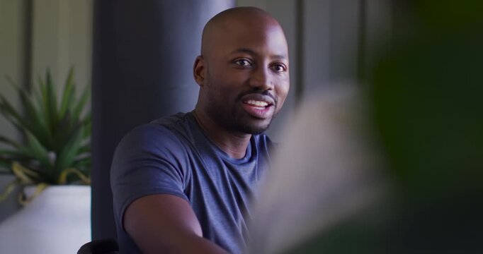 African American man navy-tee gesturing right, responding off-frame, smiling in studio with plant