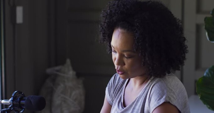 African American woman speaking, unscrewing teal bottle cap at home near microphone showing inside