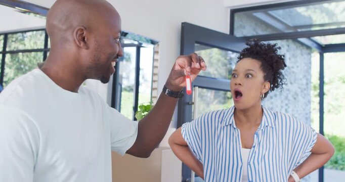 African American couple reacting to man holding red key fob at home entry, celebrating move