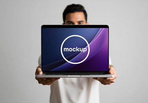 A man holding a laptop in front of him for a mockup