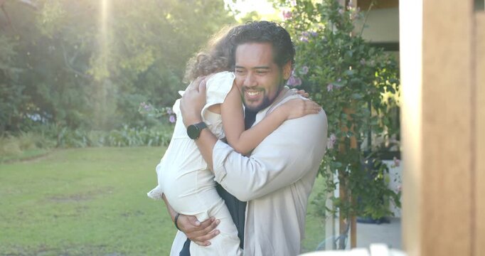 African American man lifting and holding female child on porch, comforting with smartwatch visible